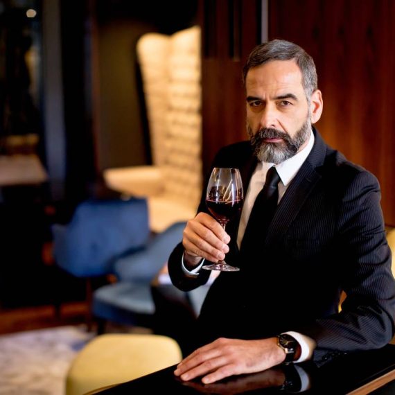 Handsome elegant businessman drinking red wine in bar