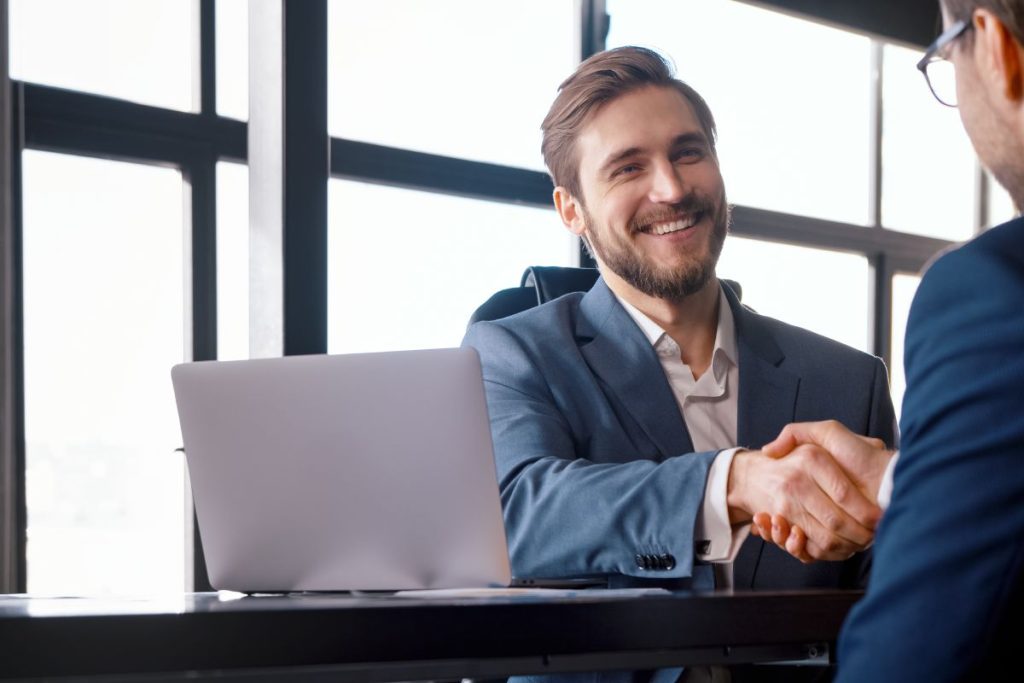 Young boss hiring new colleague shaking hands after successful job interview in a loft