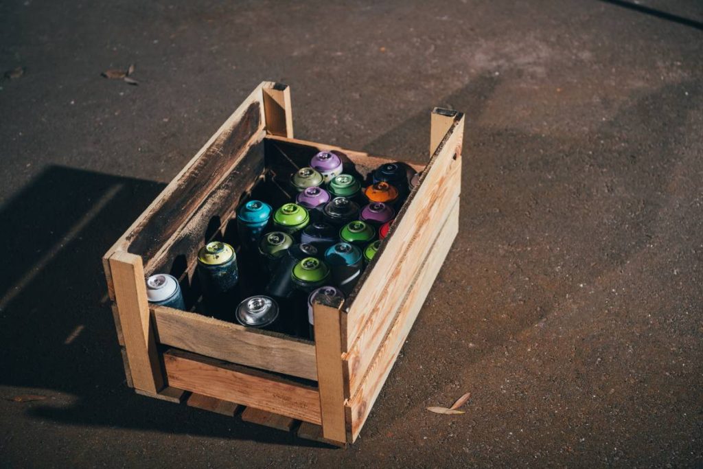 cans with aerosol paint in wooden box