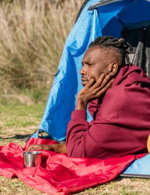 african american man lying down in camping tent relaxing in the wilderness