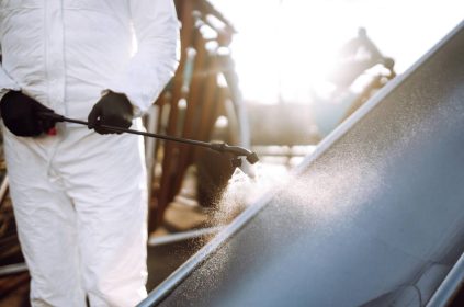 Man wearing protective suit disinfecting the playground in the sun with spray. Covid -19. Cleaning.