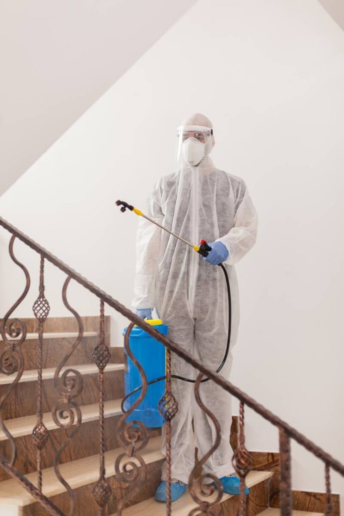 Man in protective suit disinfecting building against coronavirus contamination.