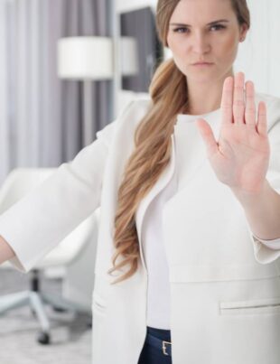 Young pretty woman standing in doorway and making stop sign with her hand